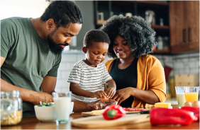 A Black child helps his parents cook a meal.