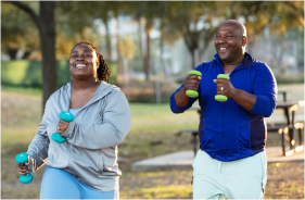 A Black couple exercises together in a park.