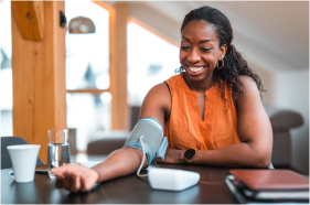 A Black adult measures their blood pressure.