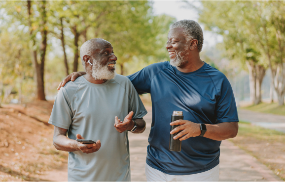 A pair of older Black friends walking outdoors together.